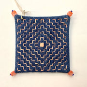 Decoratively stitched denim coaster with a geometric pattern and beads on each corner