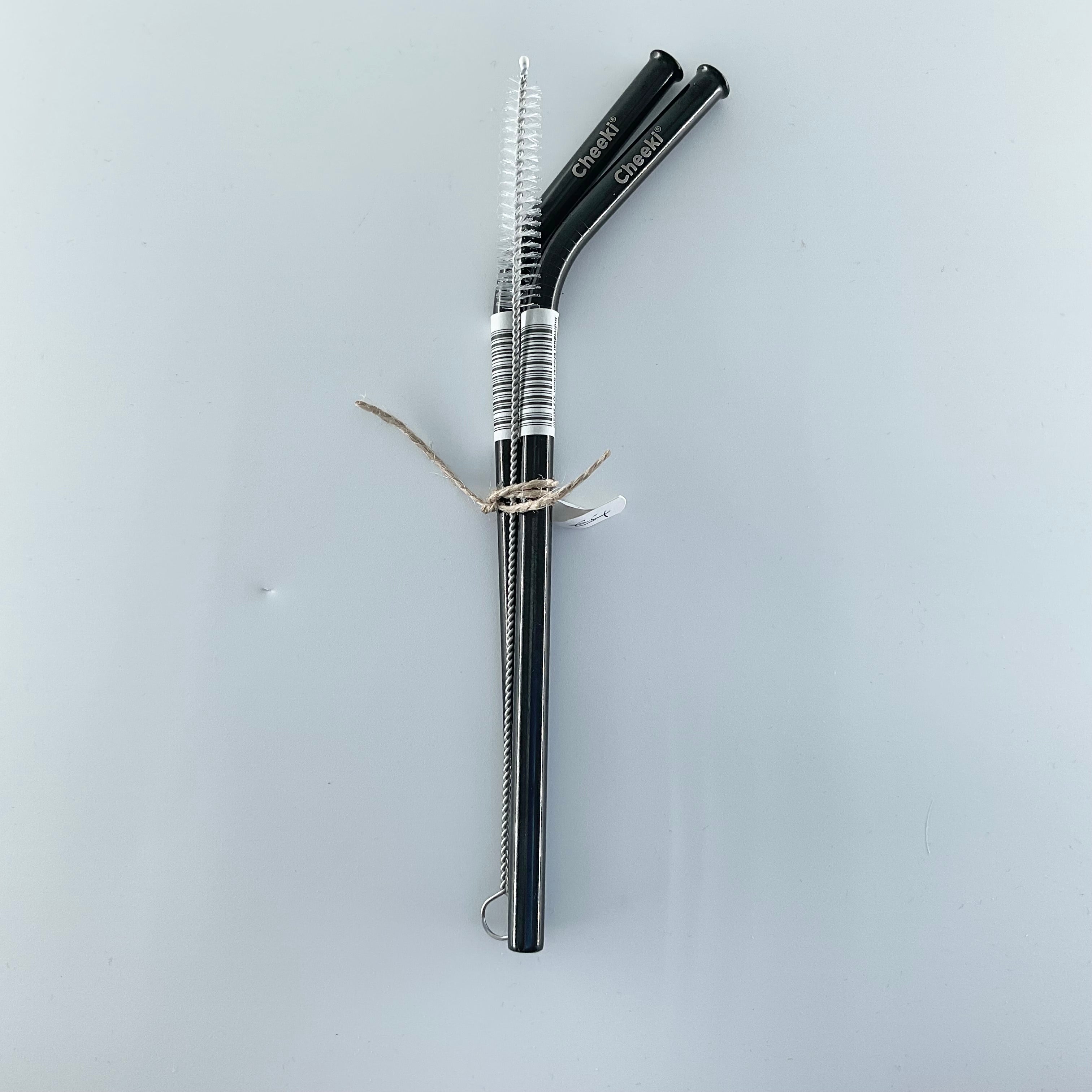 Two black metal straws with cleaning brush on a light gray background