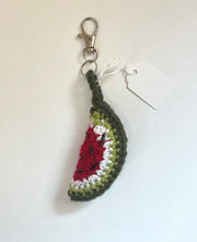 Crocheted watermelon slice keychain with black seeds made from beads on a white background