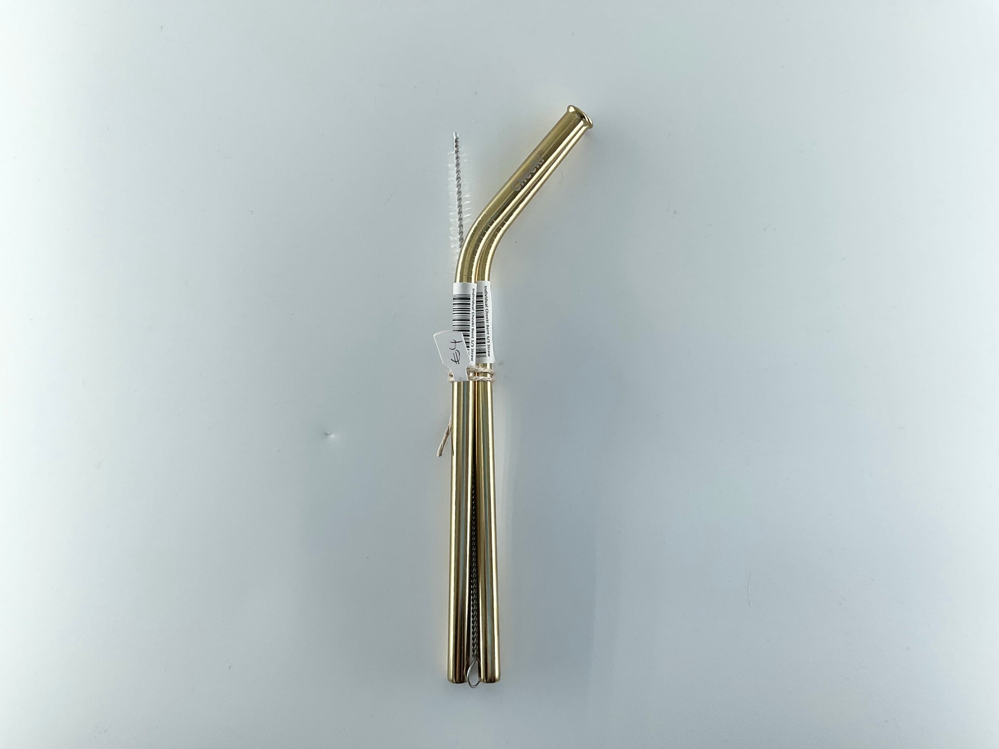 Gold metal straw with a clear label on a light gray background