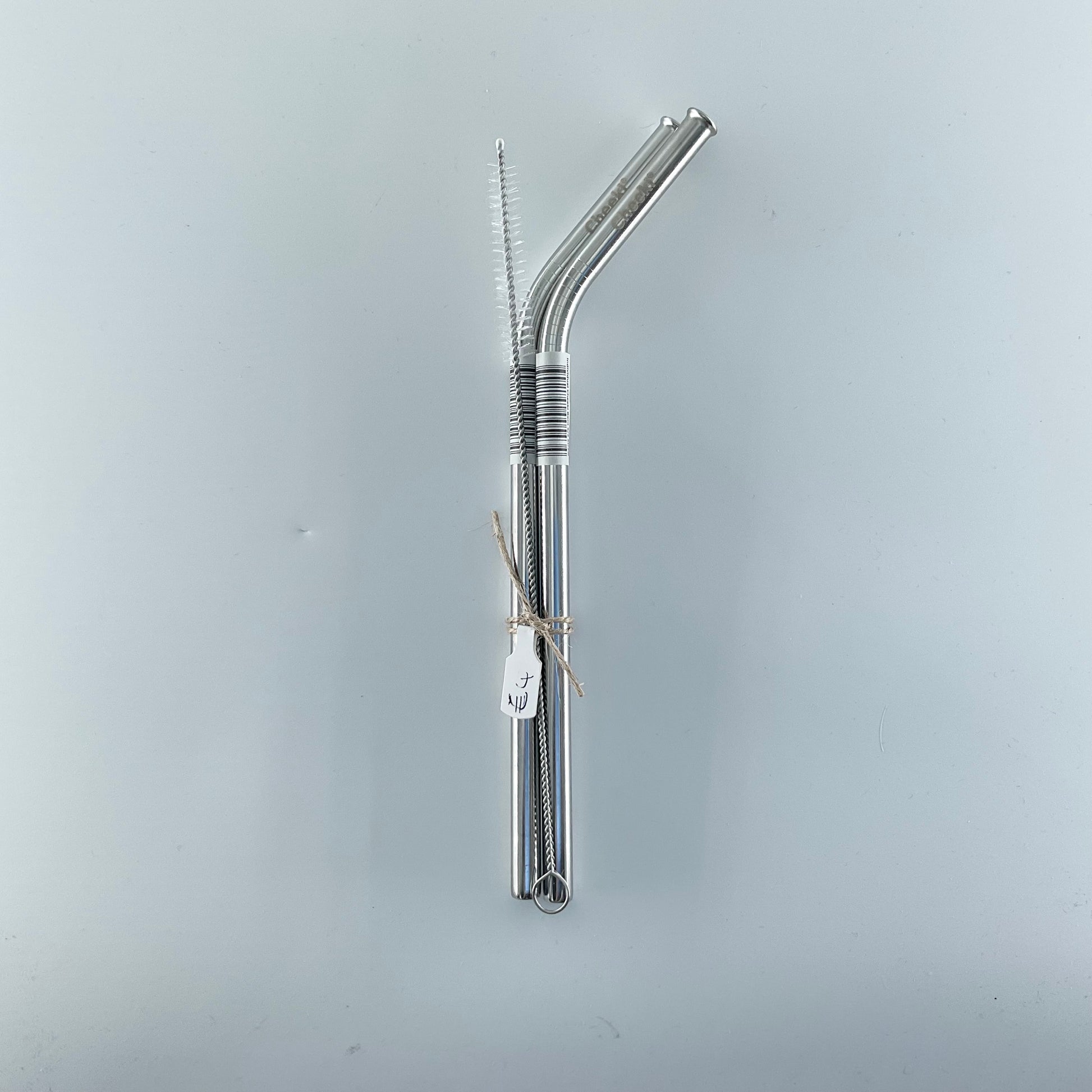 Two metal straws with a cleaning brush on a light gray background