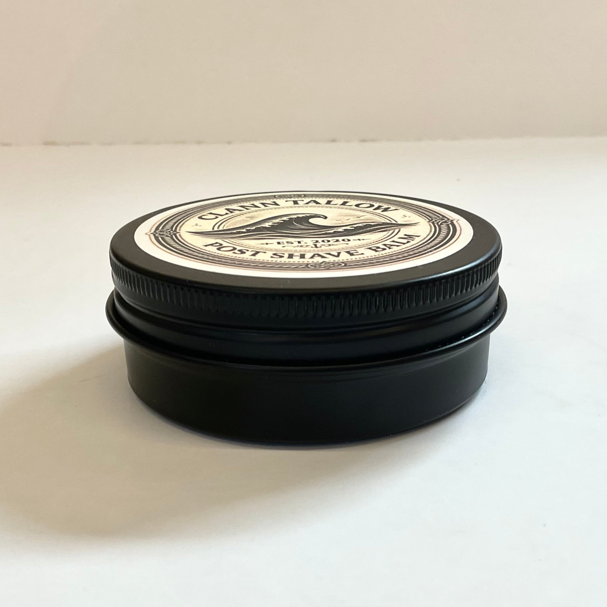 Black Clann Tallow jar with a white label on a light beige background