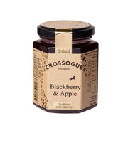 A jar of Crossogue Preserves Blackberry & Apple on a plain white background. The hexagonal glass jar contains a dark red jam, featuring a beige paper label with black text and a gold band around the neck, topped with a black lid.
