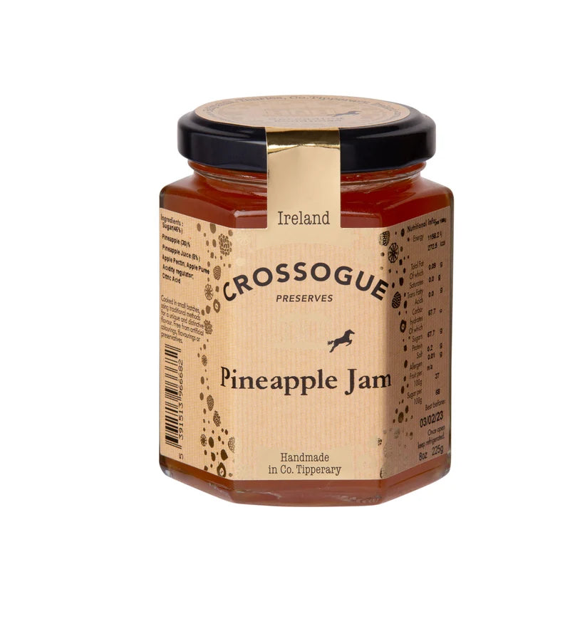 A jar of Crossogue Preserves Pineapple Jam with a beige label and a black lid, set against a plain white background.