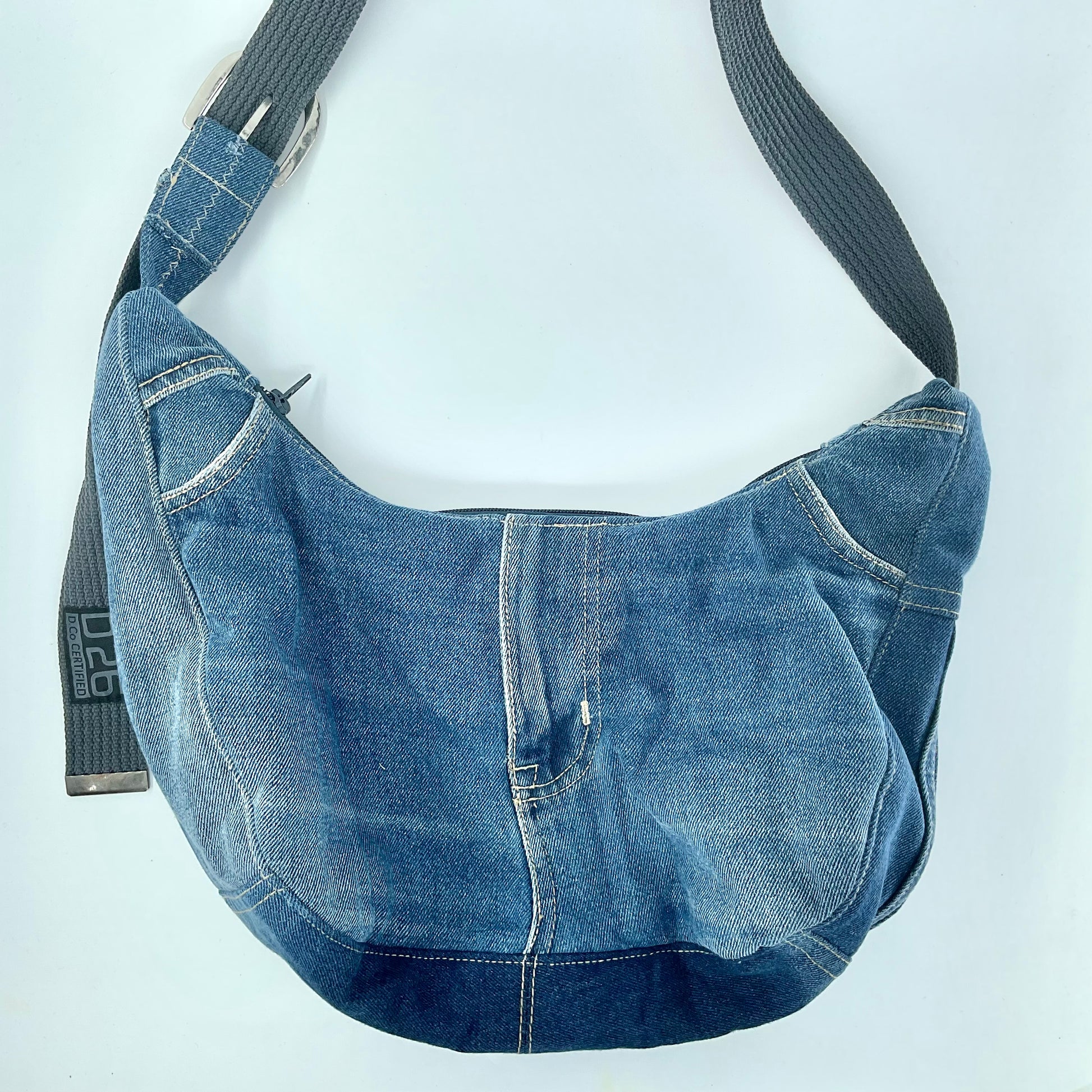 Blue denim bag with a black strap on a light gray background