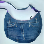 Blue denim handbag with purple interior lining on a white background