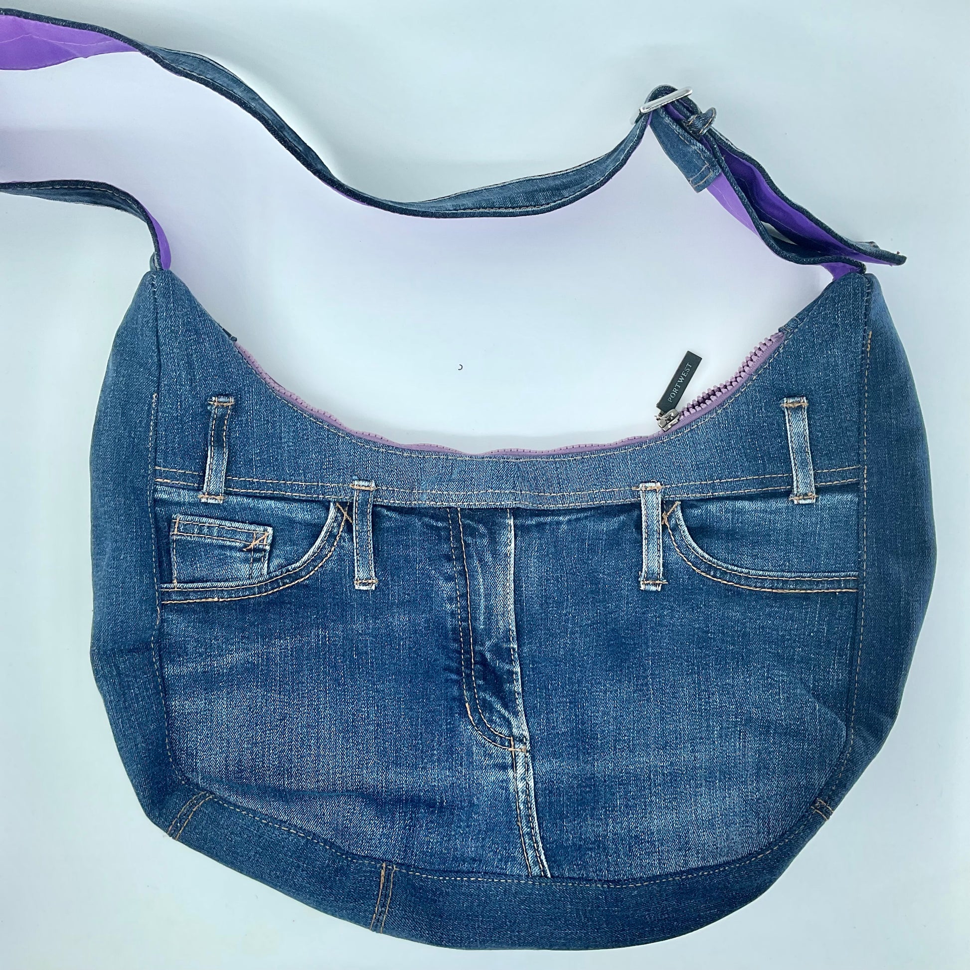 Blue denim handbag with purple interior lining on a white background
