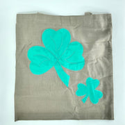 Brown tote bag with teal four-leaf clover designs on a white background