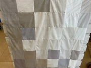 Blanket of checkered fabric panels on a wooden floor