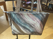 A tote bag with a pink and grey marbled pattern, featuring multiple compartments and a zippered purse pocket, displayed in a store.