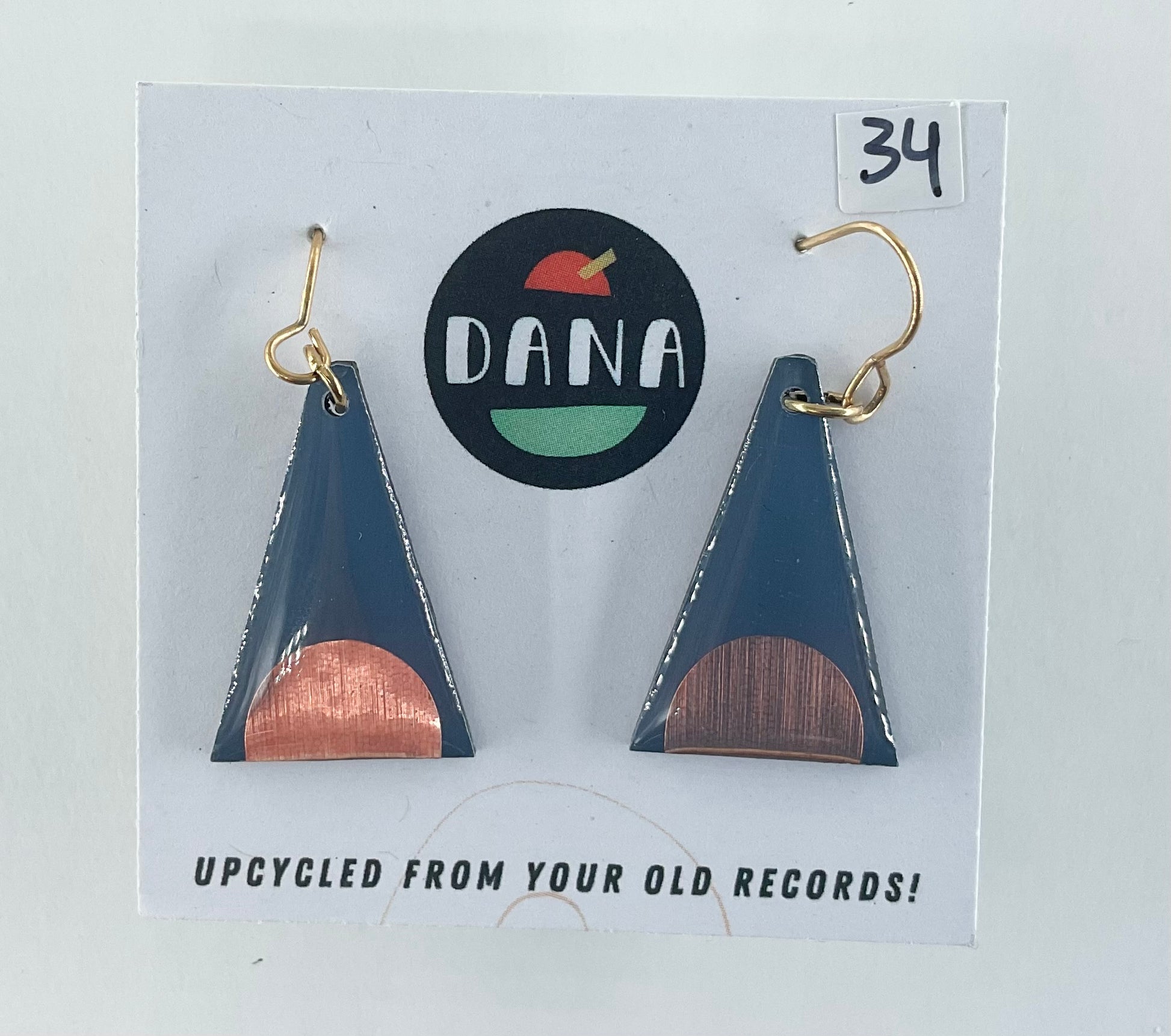 Triangular earrings with bronze and dark grey design on a Dana brand card.