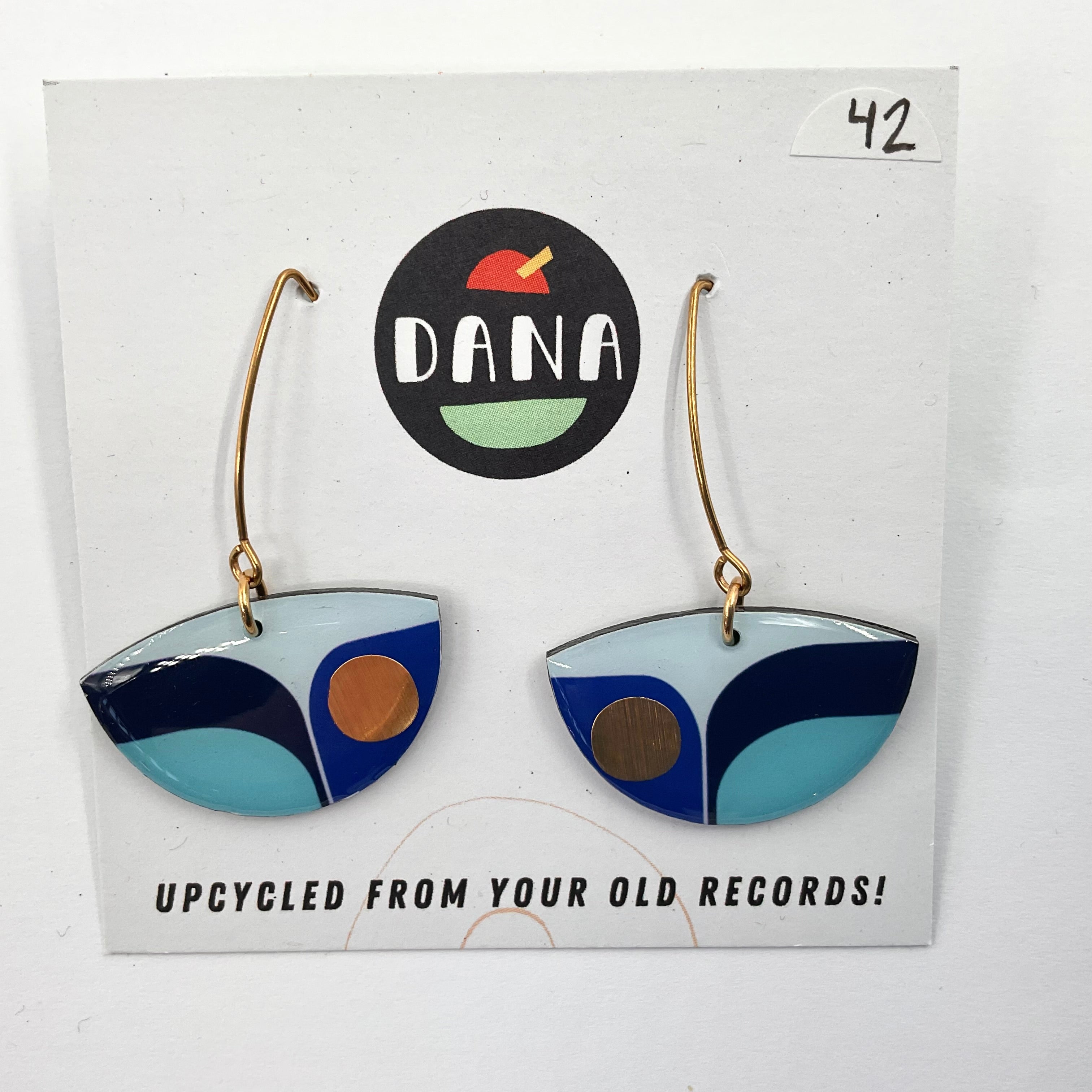 A pair of blue and white geometric patterned earrings on a Dana brand card with the text 'UPCYCLED FROM YOUR OLD RECORDS!'