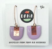 A pair of purple earrings with metallic details, labeled 'DANA' on a card that reads 'UPCYCLED FROM YOUR OLD RECORDS!'.