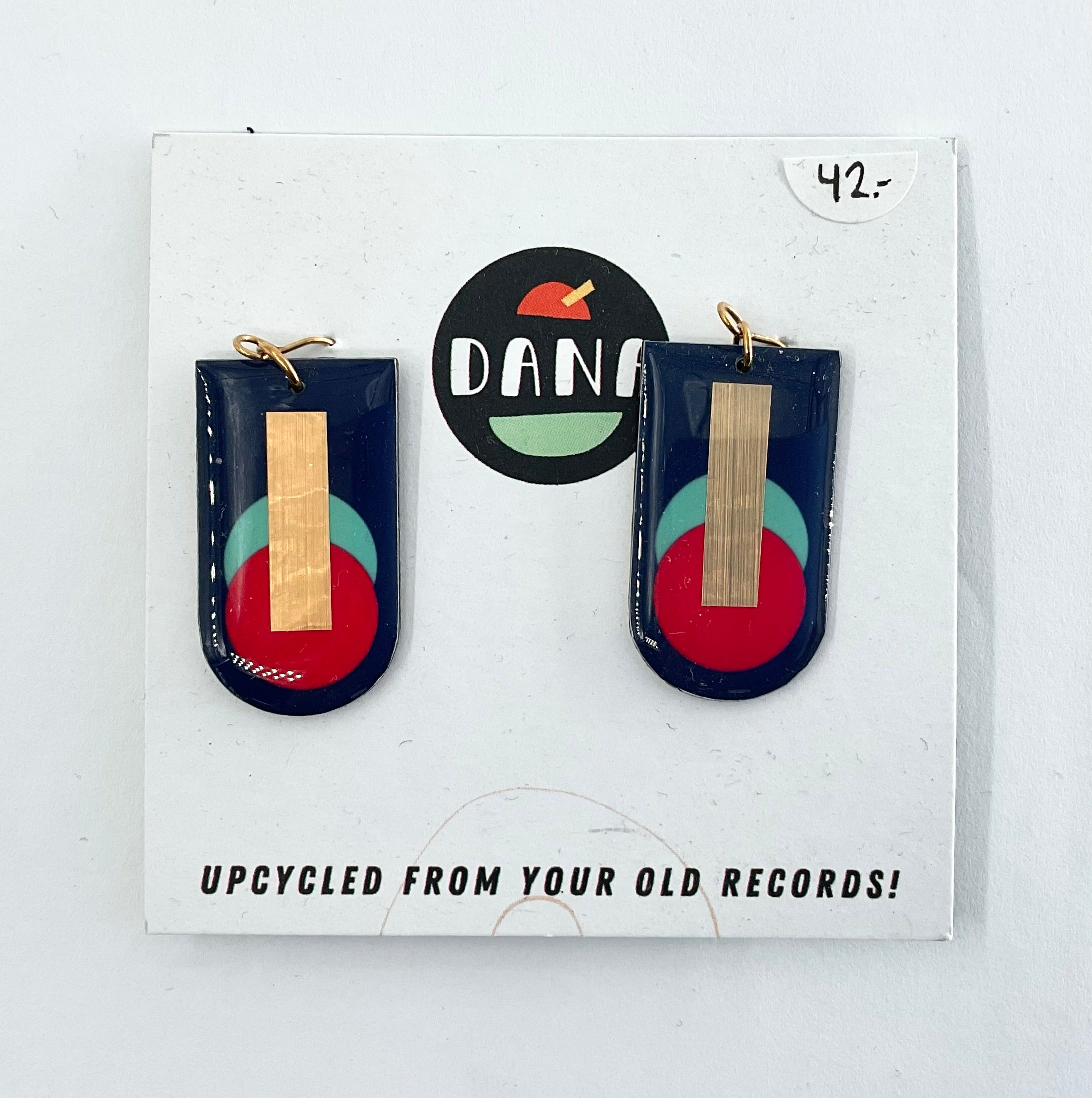 A pair of navy blue, red, turquoise, and gold earrings, displayed on a card with the brand name Dana.