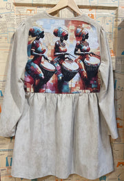 Light brown cuorderoy  dress with a colorful print of three women playing drums on a newspaper background