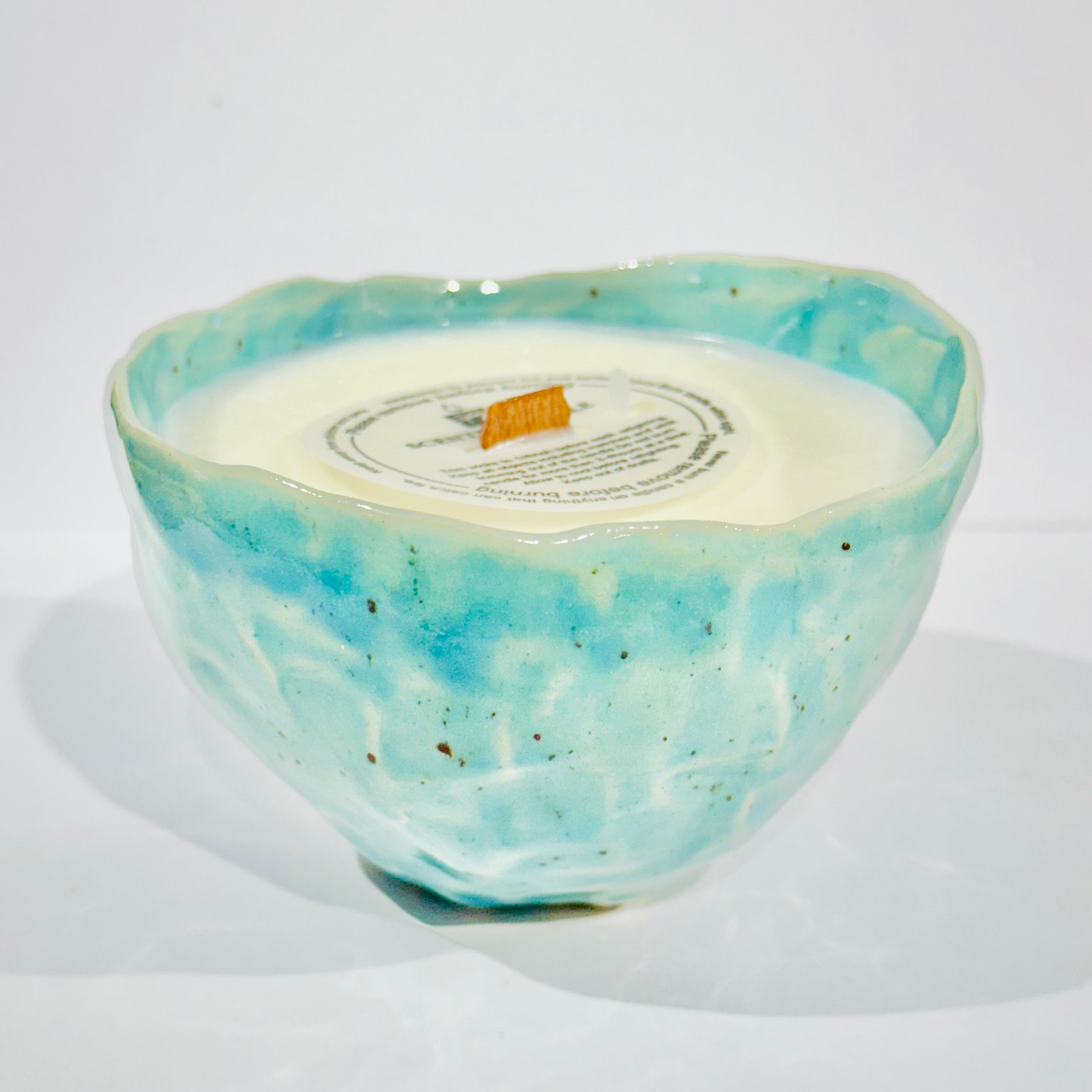 Handmade ceramic candle in a light blue and orange blossom scent, placed in a ceramic mug that can be used as a coffee/tea mug after the candle is finished.