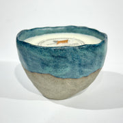 Handmade ceramic candle with blue and grey colors, placed on a white surface.
