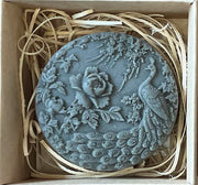 Decorative stone with peacock and floral design in a box with straw