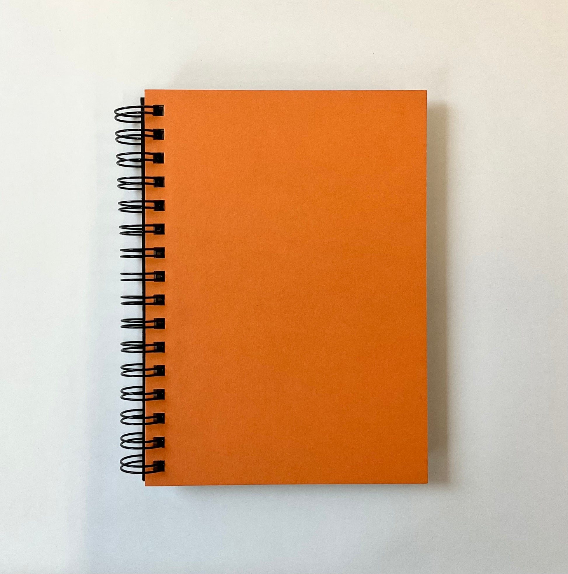 Orange spiral-bound notebook on a white background