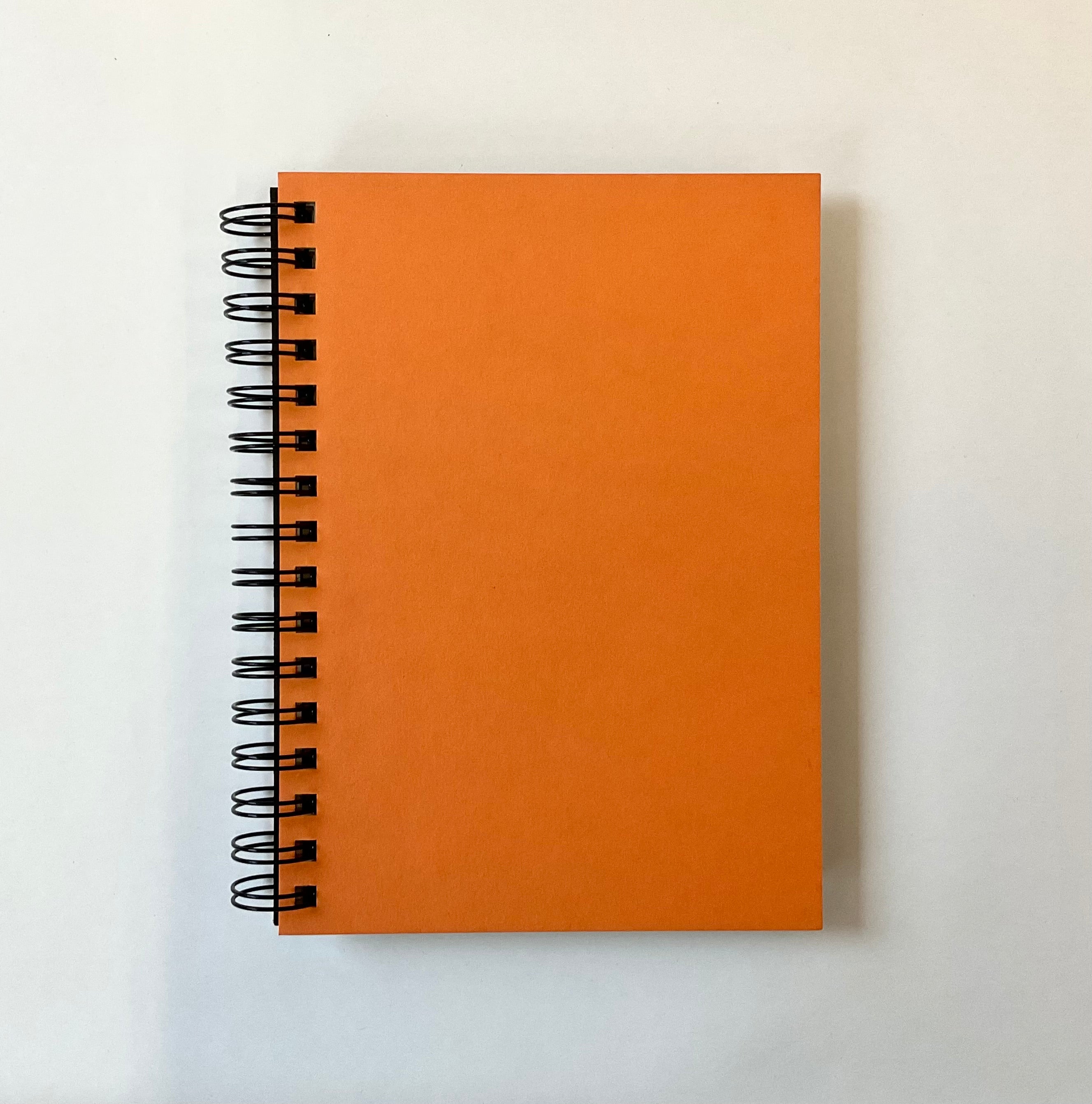 Orange spiral-bound notebook on a white background