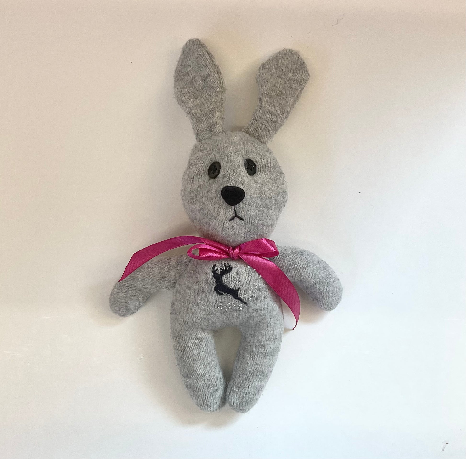 Grey stuffed bunny with a pink bow and a with a reindeer design on its chest
