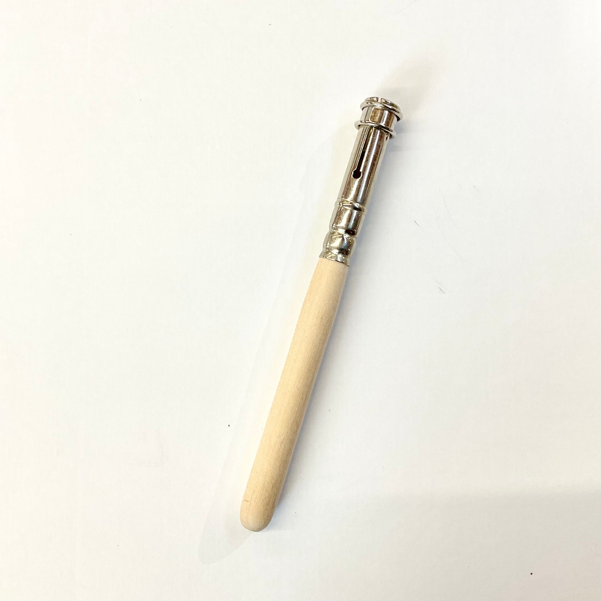 A beige-colored wooden pencil extender with a metal tip on one end, placed against a white background.