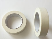 Two rolls of off-white masking tape on a plain white background, one showing the adhesive side and the other showing the cardboard core.