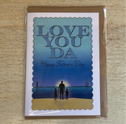 Greeting card with 'LOVE YOU DA Happy Father's Day' text and an illustration of a adult and two children on a beach at sunset