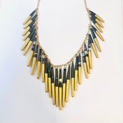 A beaded necklace with a mix of gold, black, and beige colors, made from recycled magazine paper.