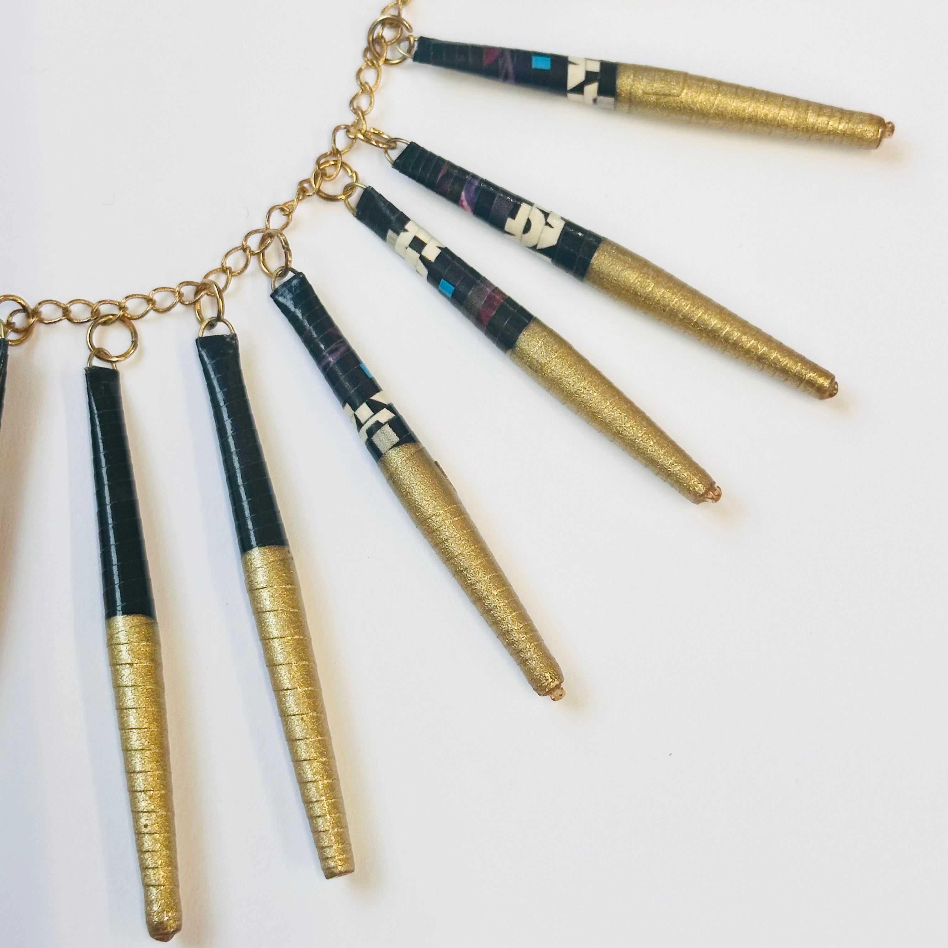 closeup of a black and gold necklace made from recycled paper beads