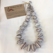 A necklace made of recycled magazine beads, predominantly in shades of black and white, with a card attached displaying 'Mothers for All' branding.