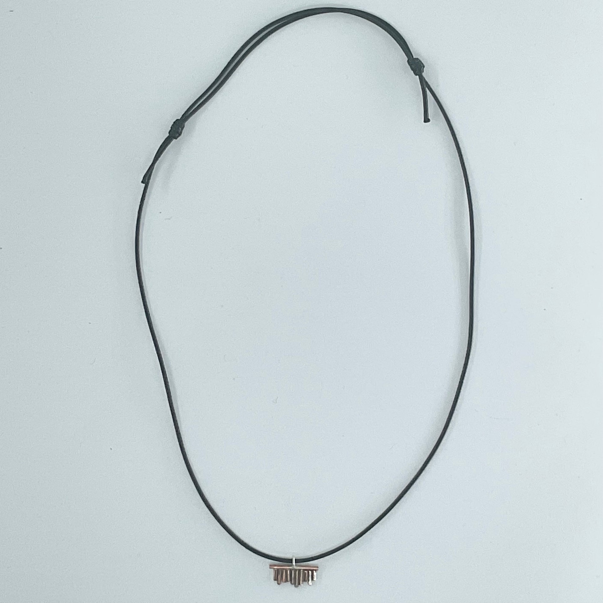 A black adjustable cord necklace with a small metallic bar pendant, displayed on a plain light gray background.