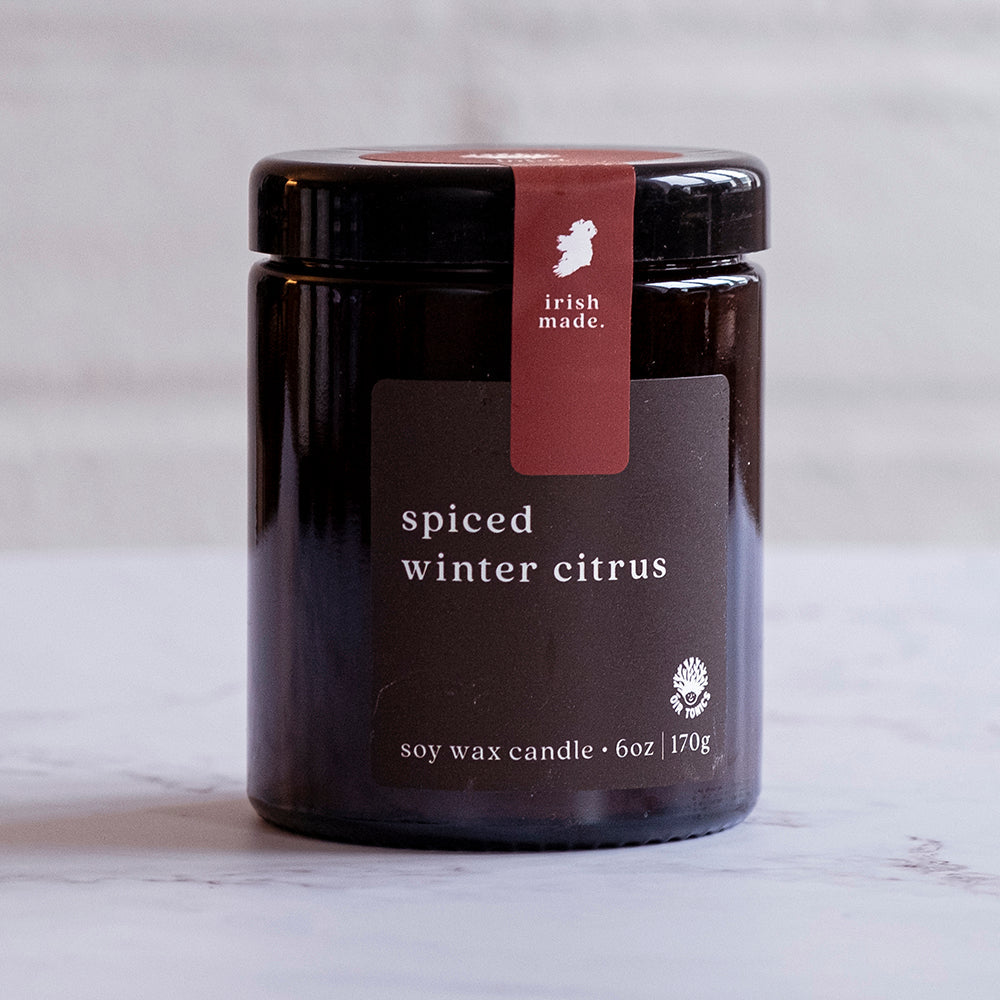 Soy wax candle labeled 'spiced winter citrus' with 'Irish Made' branding on a light background