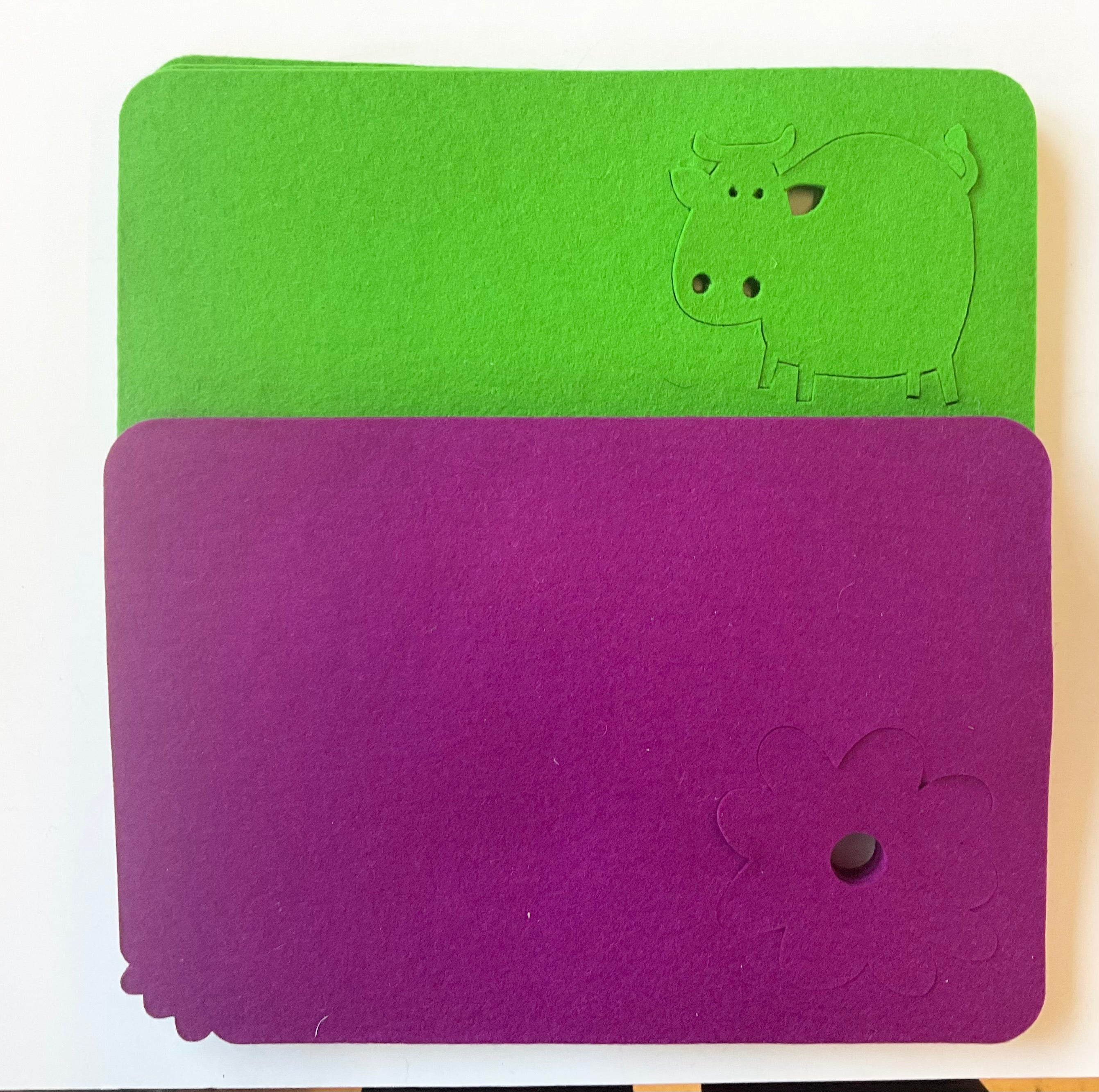 Green and purple wool placemat with a flower and cow design on a white background