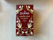 A box of Pukka Vanilla Chai Taste Adventure tea with a floral and spice design on the packaging.