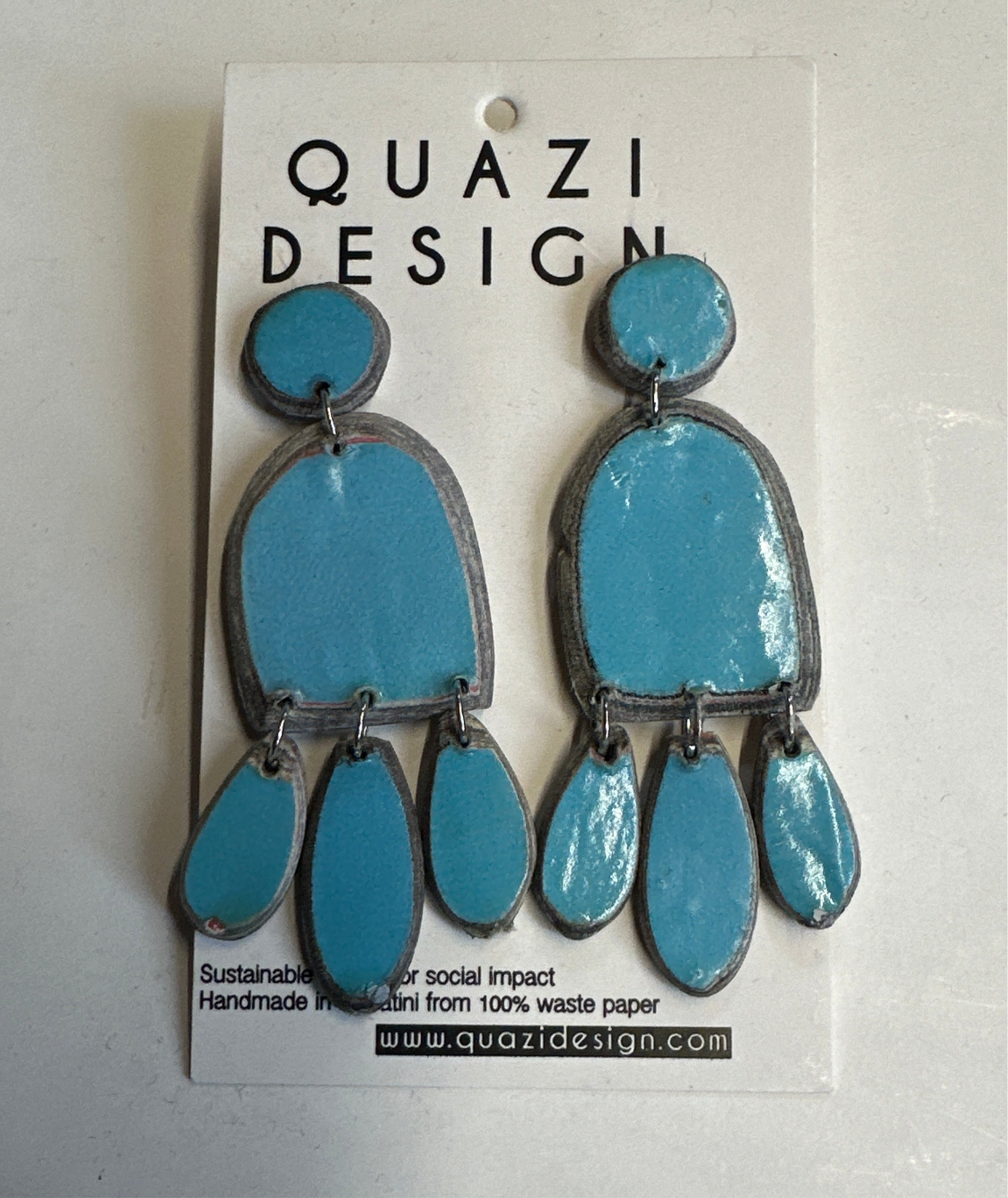 Blue earrings on a Quazi Design card with branding and sustainability information.
