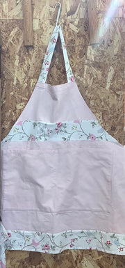 Light purple apron with floral trim hanging on a wooden surface