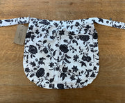 Floral-patterned apron on a wooden surface with a visible brand tag.