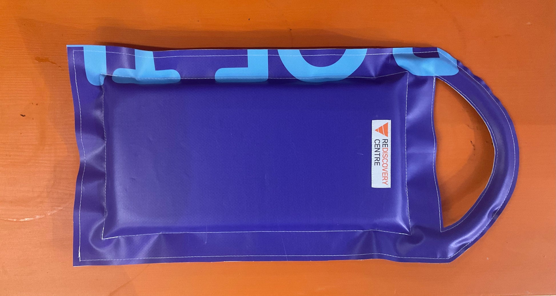 Blue plastic bag with a brand logo on a wooden surface