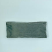 A gray silk eye mask laid flat on a white background.
