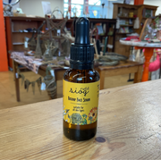 A bottle of Sióg of the Earth Rosehip Face Serum on a wooden surface, with a label featuring floral graphics and text.