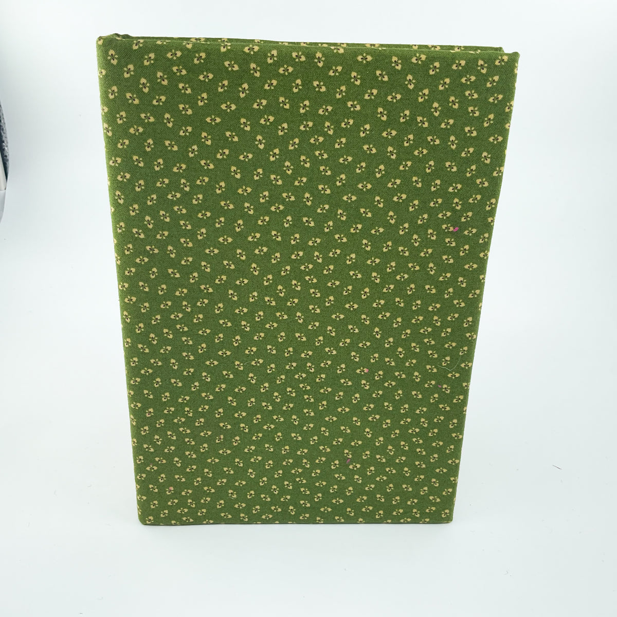 A green notebook or journal with a small repeating floral pattern, standing upright on a white background.