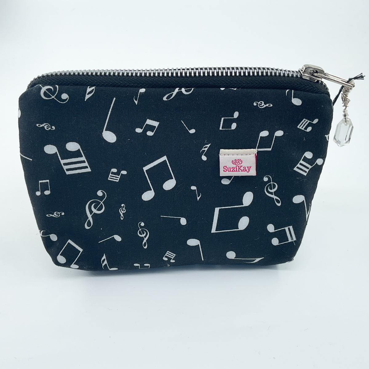 A black zippered pouch with a white musical note pattern, featuring a small pink 'SHIRRAY' brand label on the front and a silver zipper with a clear charm.