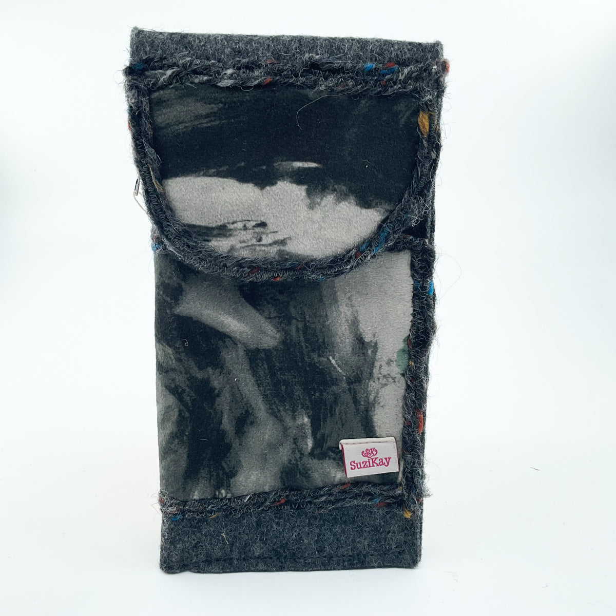 A handmade fabric pouch or sleeve made from dark gray felted wool with a black and gray abstract painted insert, featuring a small pink and white Suzikay brand tag.