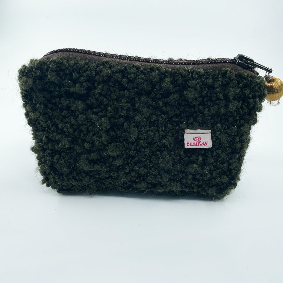 A dark olive green curly fleece zippered pouch with a small white SuziKay brand label on the front, set against a plain white background.