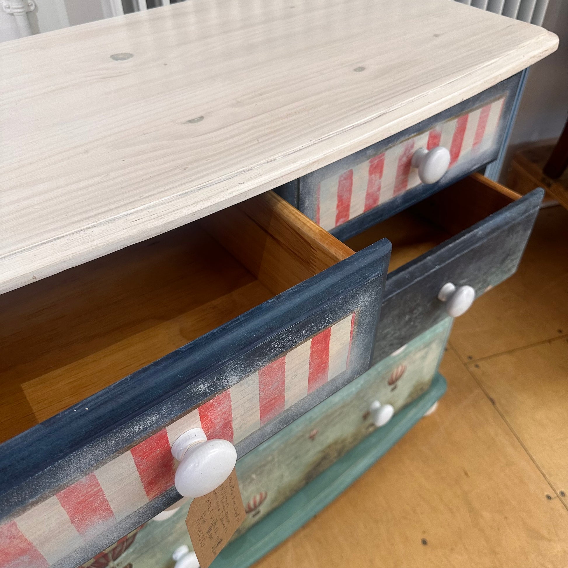Wooden dresser with striped drawer fronts on a wooden floor