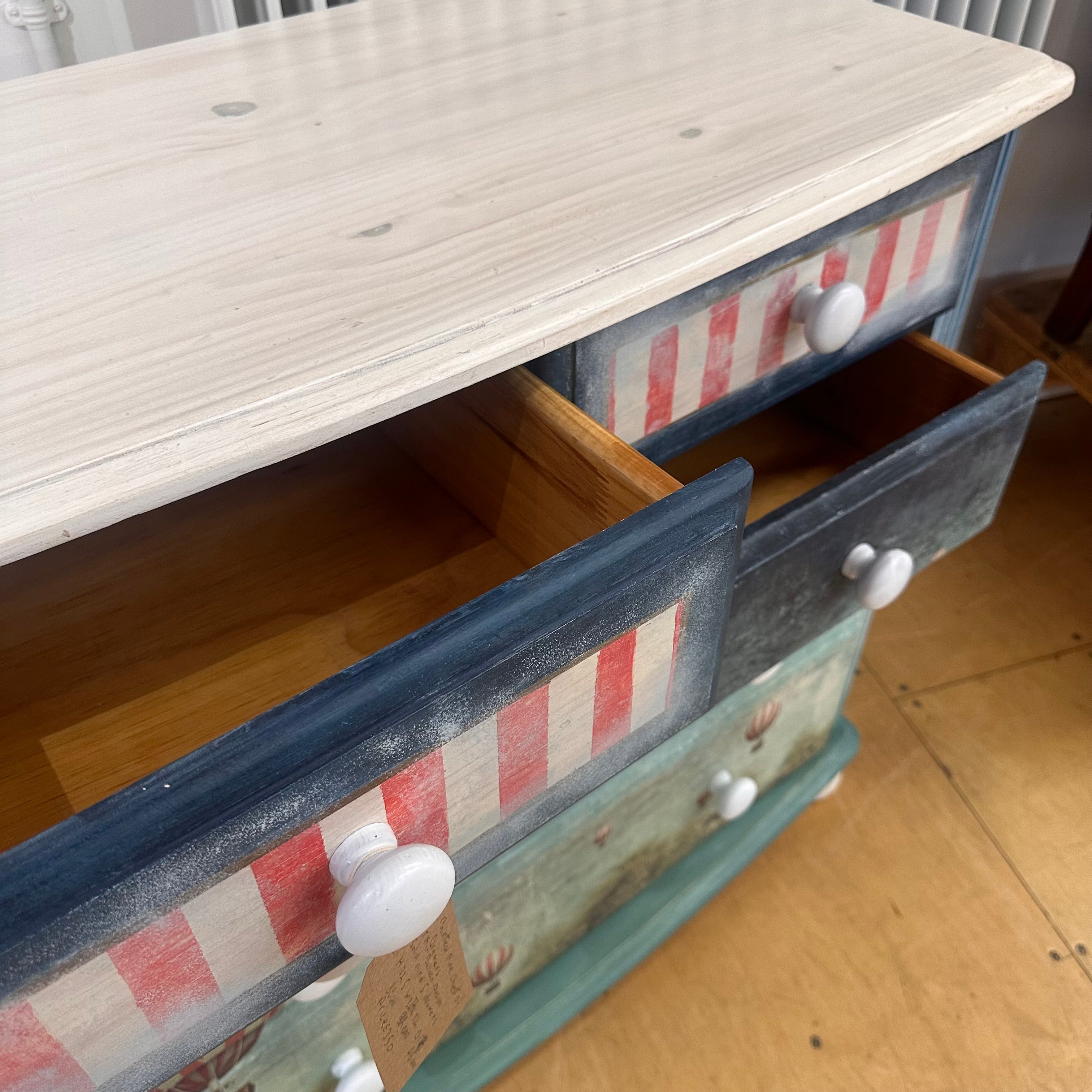Wooden dresser with striped drawer fronts on a wooden floor