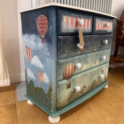 Wooden dresser with hot air balloon design on a wooden floor.