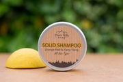 Solid shampoo bar and container with 'Three Hills Soap' branding on a wooden surface.