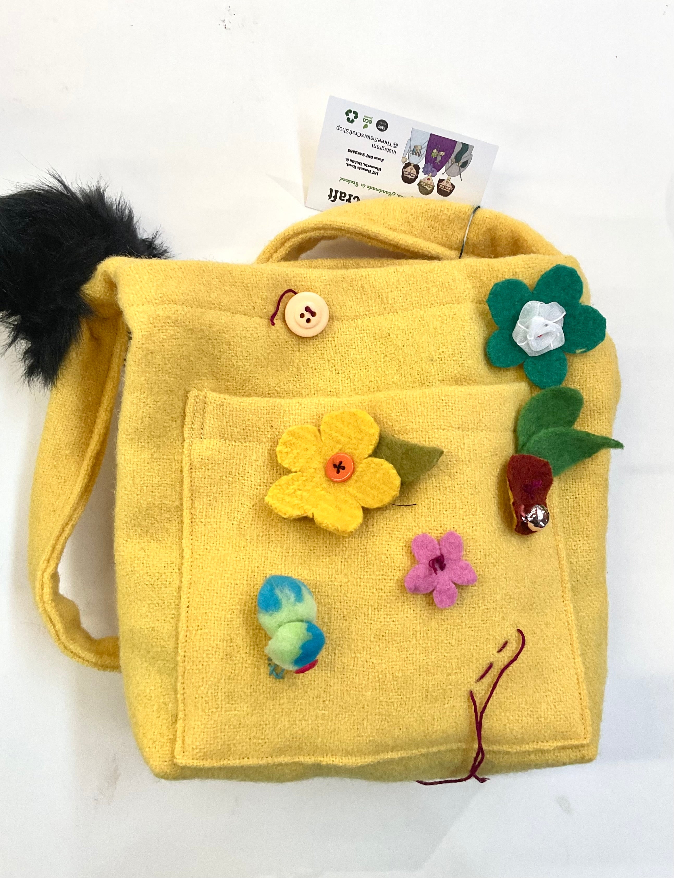Yellow children's wool bag with floral decorations on a white background